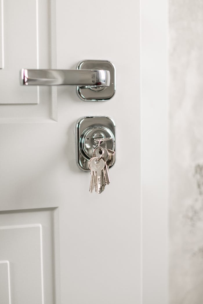 Close-up of a modern silver door handle with keys hanging in the lock, symbolizing security.